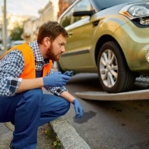 Closeup view on male road worker wearing uniform monitoring car loading process on evacuator platform